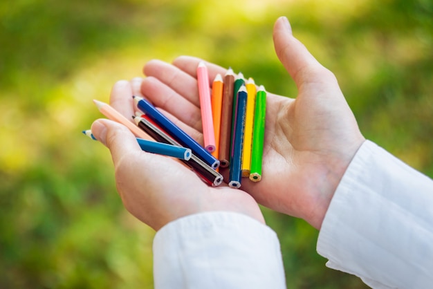 Mädchen, das viele bunte hölzerne Bleistifte in den Händen hält.