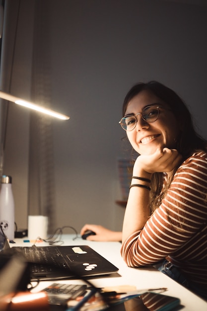 Mädchen, das von zu Hause aus am Laptop arbeitet, oder Student, der von zu Hause aus studiert oder freiberuflich tätig ist. Online-Arbeit, Late-Night-Schreibtischarbeit, Homeoffice