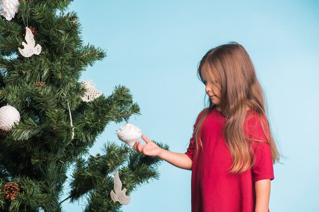 Mädchen, das Weihnachtsbaum mit Spielzeug und Kugeln verziert