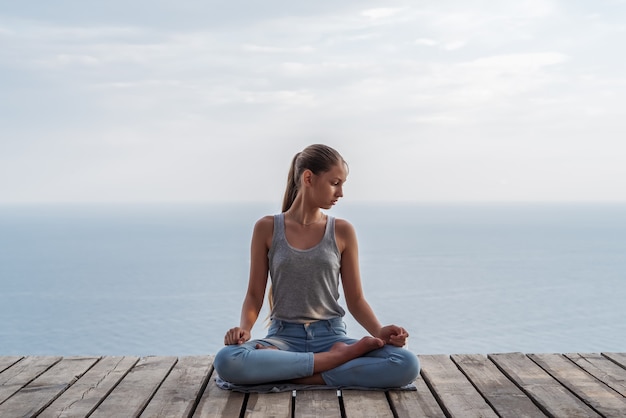 Mädchen, das Yoga auf dem Hintergrund des Meeres tut