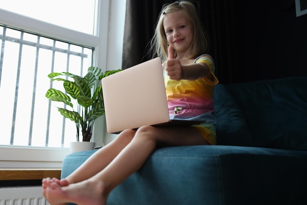 Mädchen, das zu Hause auf der Couch sitzt und einen Laptop hält