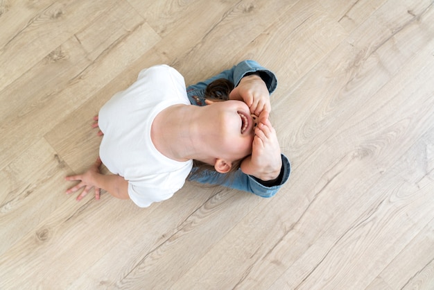 Mädchen, das zu Hause Yoga praktiziert und sich in der Raja Bhudjangasana-Übung, Königskobra-Pose, ausdehnt. Draufsicht