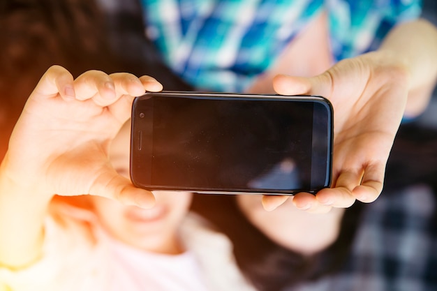 Mädchen, die auf Decke liegen und Telefon zusammenhalten