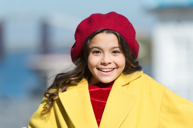 Mädchen entzückendes Kind gehen defokussierten Hintergrund. Modisches Mädchen genießen Spaziergang am sonnigen Frühlingstag. Kinderhelles Hutbarett und warmer Mantel. Trend im französischen Stil. Unbeschwerter entspannter Spaziergang. Gesundheitliche Vorteile des Gehens.