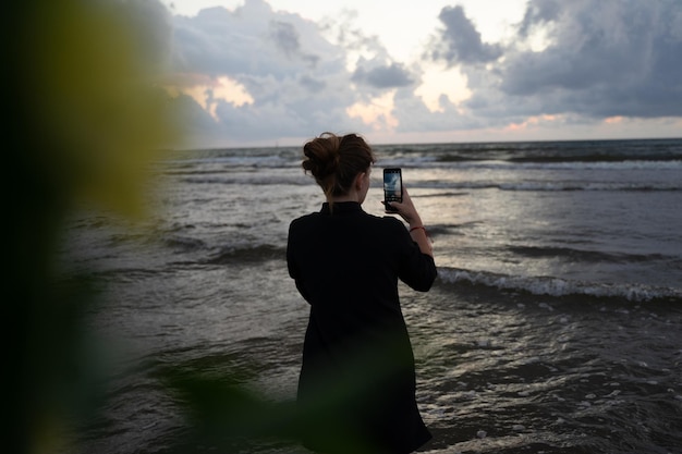 Mädchen filmen einen bewölkten Sonnenuntergang am Telefon