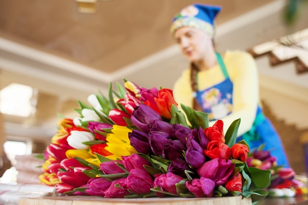 Mädchen Florist verpackt schöne Tulpen in einem Blumenladen in Kraftpapier