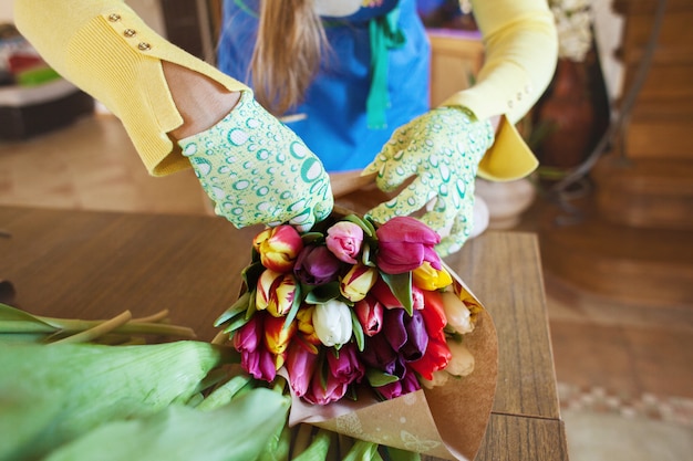 Mädchen Florist verpackt schöne Tulpen in einem Blumenladen in Kraftpapier