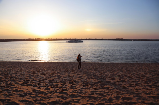 Mädchen fotografiert am Strand bei Sonnenuntergang oder Sonnenaufgang