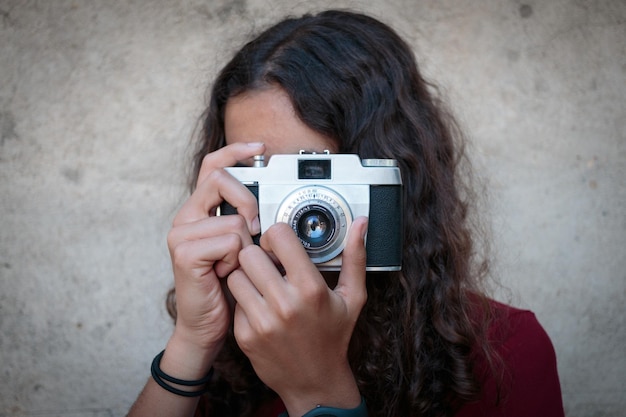 Mädchen fotografiert mit Kamera an der Wand