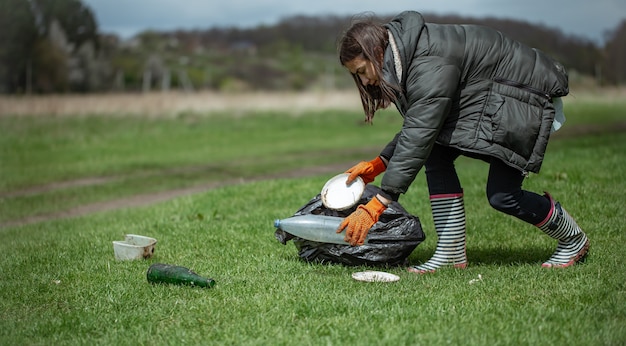 Mädchen-Freiwillige sammelt Müll im Wald, kümmert sich um die Umwelt.