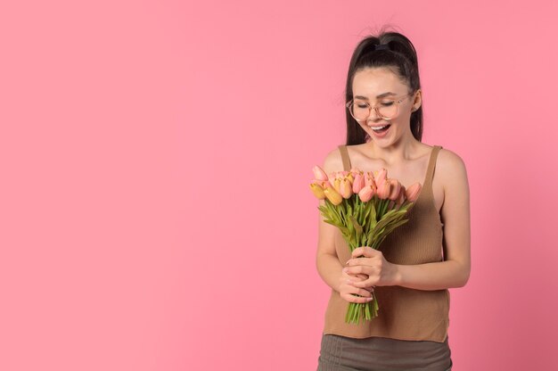 Mädchen freut sich mit einem Blumenstrauß auf rosa Hintergrund