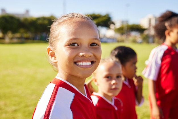 Mädchen-Fußballer-Porträt und Feld für das Training von Teamwork und Gruppenvielfalt mit einem Lächeln Junge weibliche Kinder-Fußballgruppe und glücklich über Teambuilding-Lernen und -Entwicklung mit aufgeregtem Gesicht