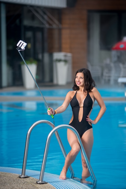 Mädchen gegen Schwimmbad macht selfie Foto