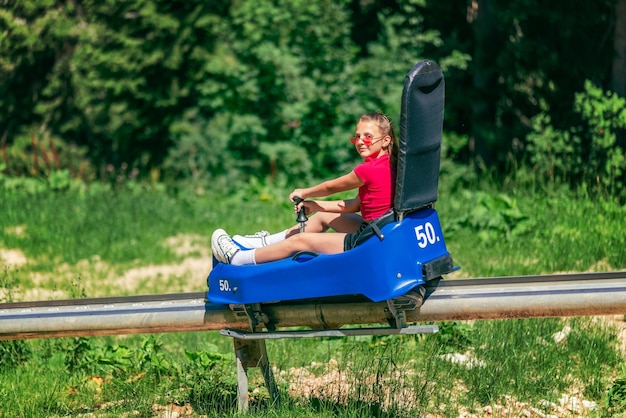 Mädchen gehen im Sommer auf der Bergachterbahn bergab Skipiste Sommertourismus und Spaß am Bergkonzept