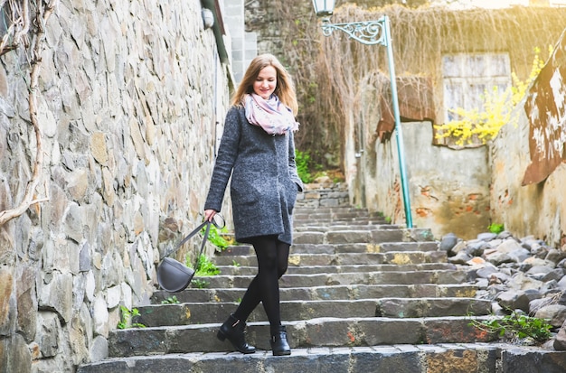Mädchen geht in der schmalen Straße mit Steinpflaster. Stilvolle Frau. Mittelalterliche Laterne. Treppen in der Stadt.