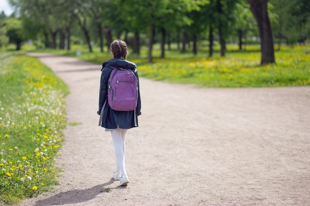 Mädchen geht mit lila Aktentasche zur Schule