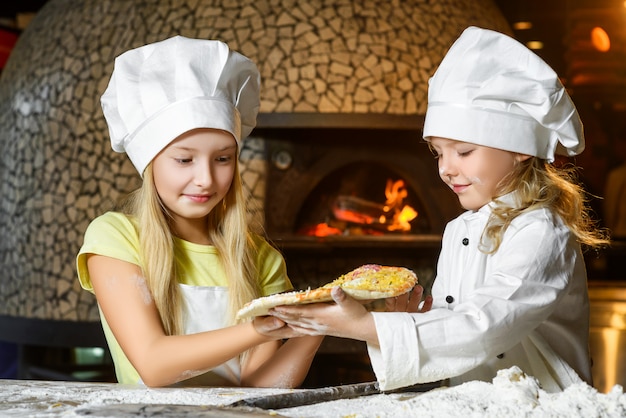 Mädchen gekleidet als Köchin, die Pizza vorbereitet