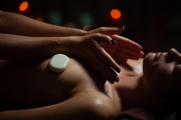Mädchen genießen therapeutische Massage mit Öl im Spa mit dunkler Beleuchtung, Nahaufnahme