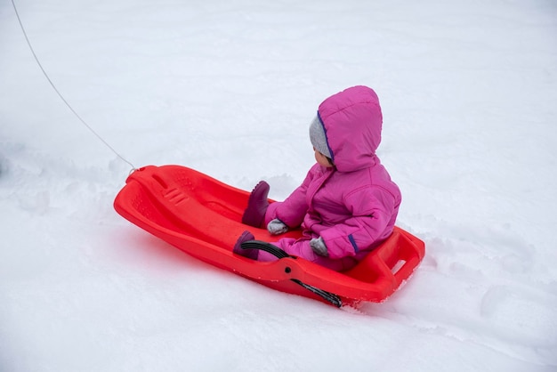 Mädchen genießt eine Schlittenfahrt im Freien im Schnee