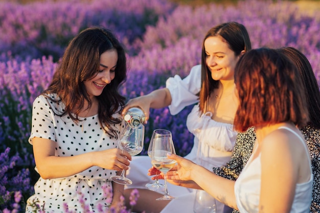 Mädchen gießt Weißwein aus einer Flasche in Gläser