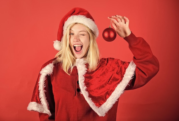 Mädchen glücklich fröhlich tragen Santa Kostüm feiern Weihnachten halten Ball Dekor Frohe Feiertage Konzept Lieblingszeit Jahr Weihnachten Genießen Sie die Feier mit dem richtigen Kostüm für Maskerade Frohe Weihnachten