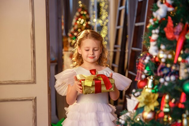Mädchen hält ein Geschenk in der Nähe von Weihnachtsbaum
