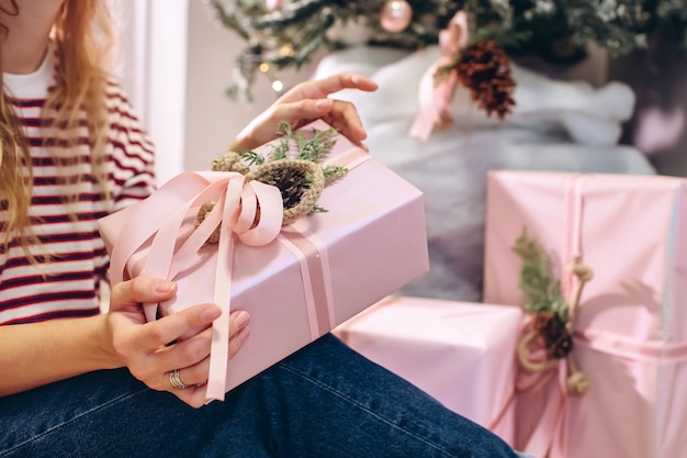 Mädchen hält ein Geschenk, Weihnachtsbaum, rosa Schachtel mit einem Geschenk