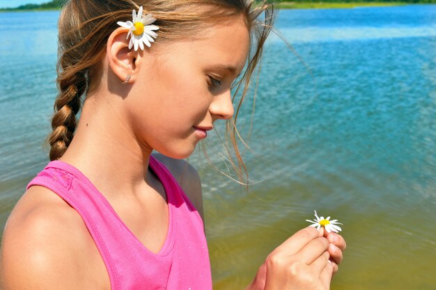 Mädchen hält eine Kamillenblume nahe dem Meer