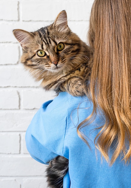 Mädchen hält eine Katze auf ihrer Schulter. Familienkonzept.