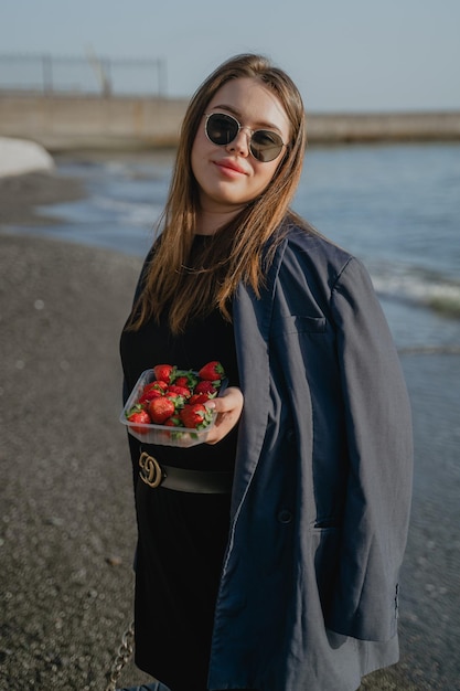 Mädchen hält einen Korb mit Erdbeeren am Strand