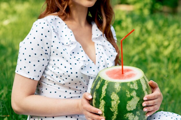 Mädchen hält ganze Wassermelone mit Cocktailstroh