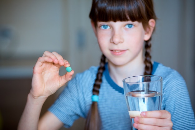 Mädchen hält Pille mit Glas Wasser