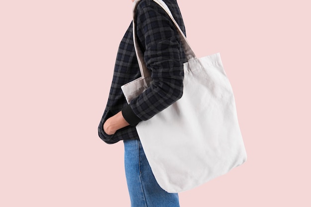 Mädchen hält Tasche Leinwand Stoff für Modell leere Vorlage auf grauem Hintergrund isoliert.