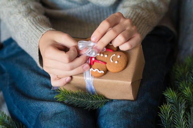 Mädchen Hände gebunden Lebkuchenmann auf einer Geschenkbox Vorbereitung für Weihnachten und Neujahr