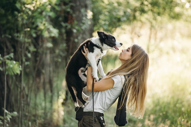 Mädchen halten auf ihren Händen Schwarzweiss-Border-Collie-Hundewelpe im Feld