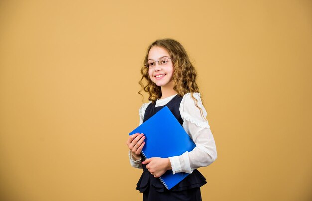 Mädchen halten Lehrbuch Ordner Test Vorbereitung auf Prüfungen in der Bibliothek Formelle Kleidung für kleine Kinder Formelle Bildung und Homeschooling Wissen prüfen Schulprüfungskonzept Vorbereitung auf die Prüfung Abschlussprüfung kommt