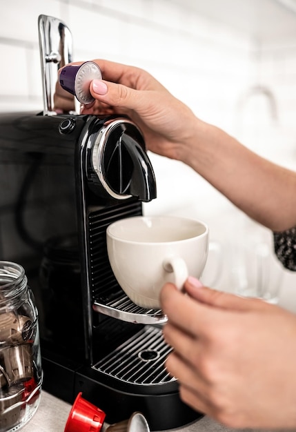 Mädchen hand legte Kapsel zu Kaffeemaschine zu Hause Nahaufnahme Frau bereitet uns italienisches Koffeingetränk zu