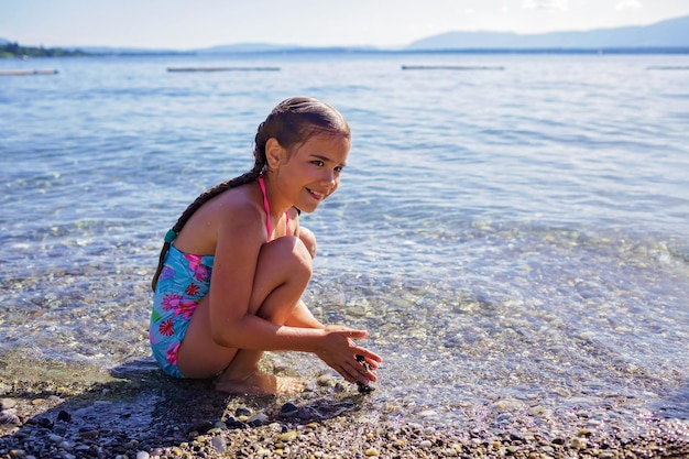 Mädchen hat Spaß und spielt mit Steinen am Kiesstrand am Genfer See Sommerferien und Reisen