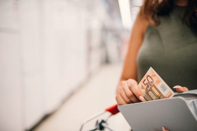 Mädchen holt eine Banknote von fünfzig Euro aus der Brieftasche. Nahansicht.