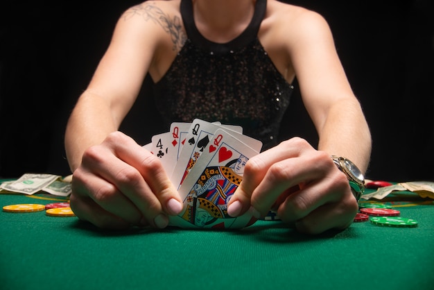 Mädchen im Abendkleid, das Poker spielt und Karten betrachtet