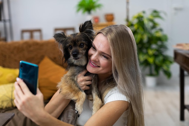 Mädchen im Arm hält Hund und sie machen zusammen ein Selfie Multi-Rasse-Hund