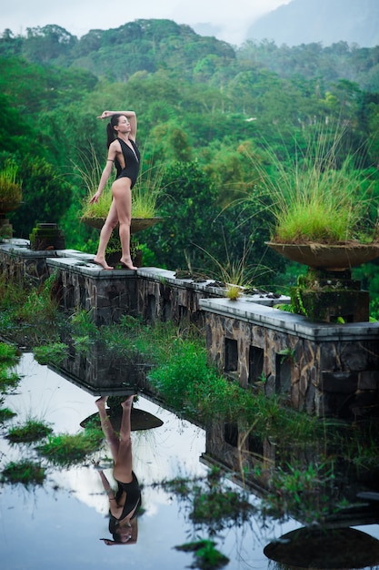 Mädchen im Badeanzug im mystischen verlassenen faulen Hotel in Bali mit blauem Himmel.