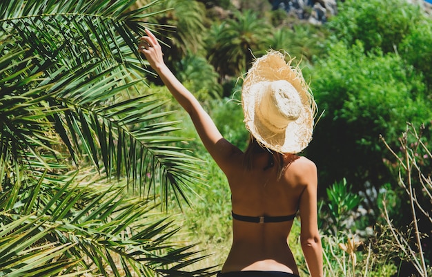 Mädchen im Bikini und im Hut haben Rest im Palmenwald