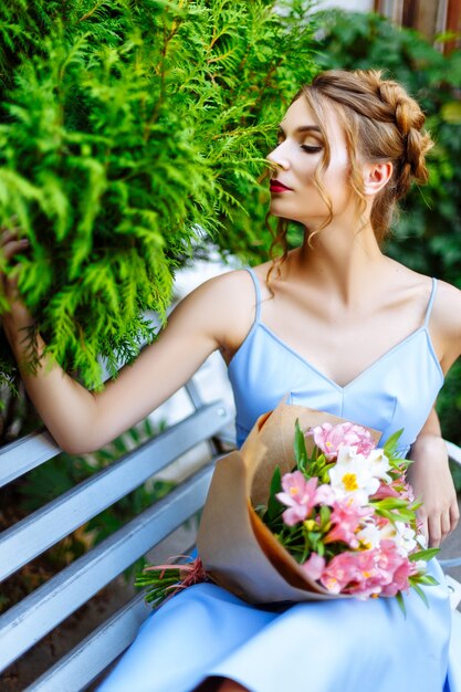 Mädchen im blauen Kleid mit Blumenstrauß auf der Straße