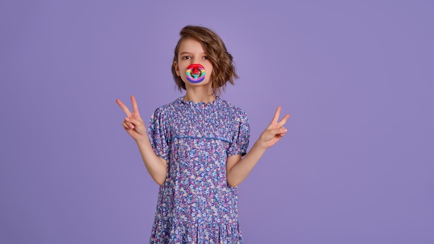 Mädchen im blauen Sommerkleid mit Blumendruck, das Pop-It-Anti-Stress-Spielzeug auf Lavendel hält