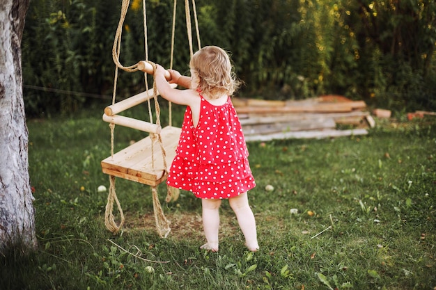 Mädchen im Garten spielt mit Schaukeln Baby spielt alleine im Garten