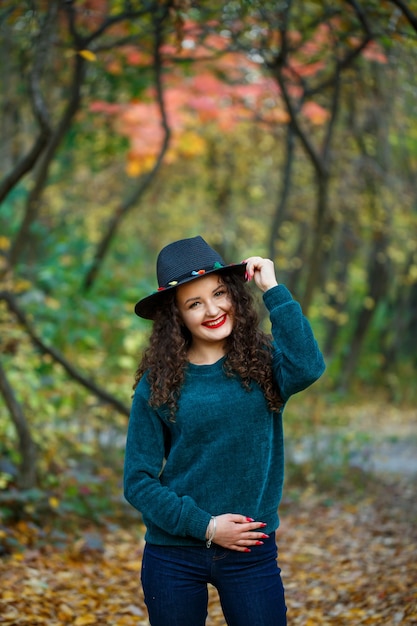 Mädchen im herbstlichen Wald mit Hut in der Hand