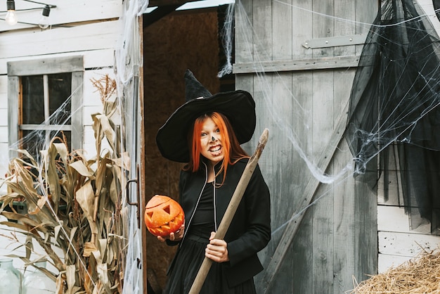 Mädchen im Hexenkostüm mit Besen auf einer Halloweenparty