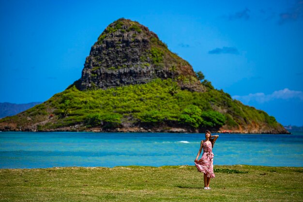 Foto mädchen im langen kleid geht entlang der küste im kualoa regional park auf oahu, hawaii, mit blick auf mokolii