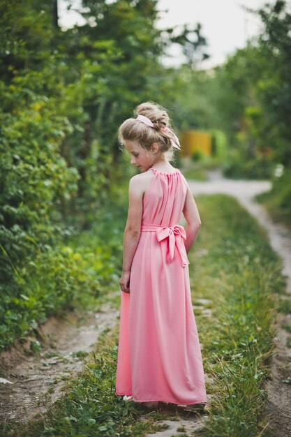 Foto mädchen im langen rosa kleid, das auf naturhintergrund posiert 6649